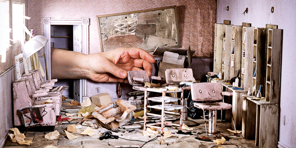 artist lori nix hands placing a table in a model of a post apocolyptic hair salon