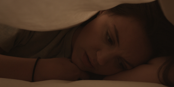 woman talking underneath sheets in bed