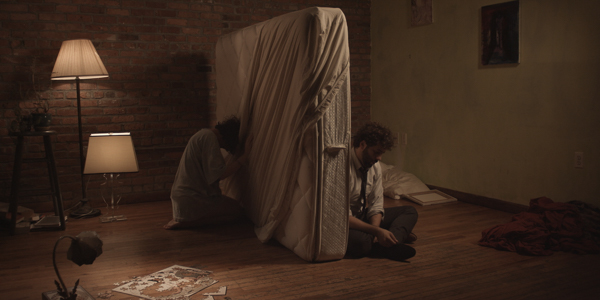 two people on either side of a flipped vertically mattress